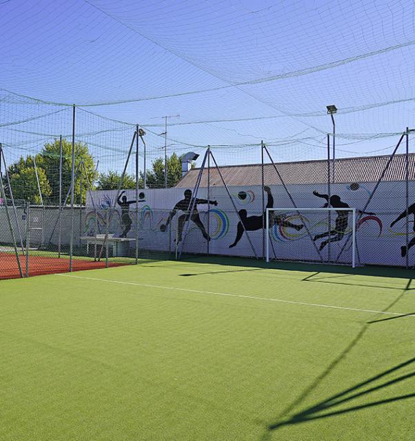 Campo sportivo con rete di protezione e murales colorati.